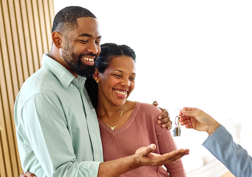 Young black couple receiving keys of new apartment from their real estate agent, standing in the new home