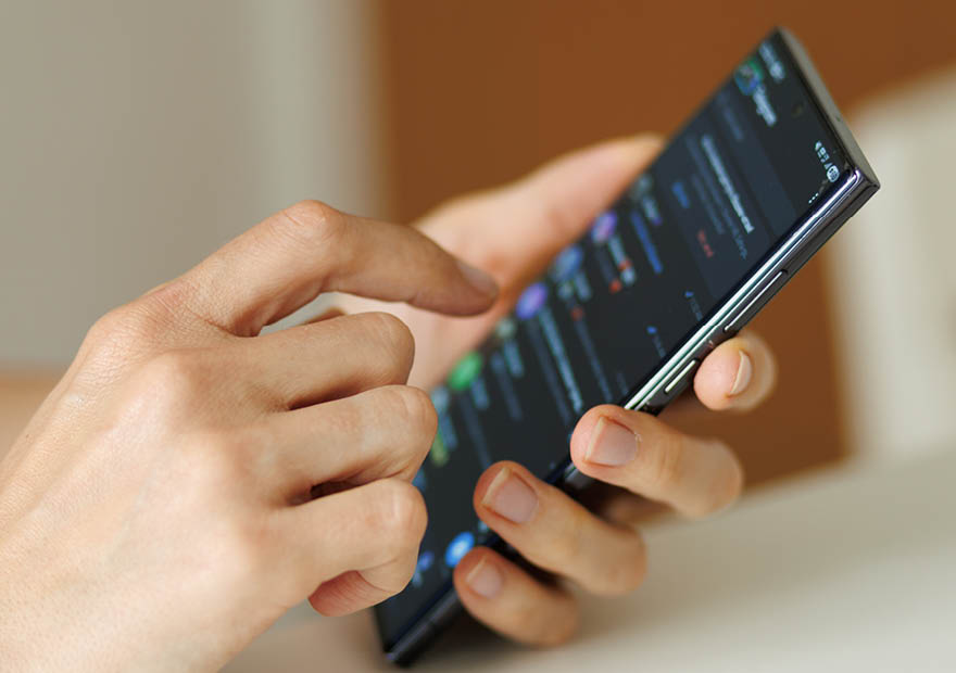 Hands using a smartphone to check notifications browse mobile apps read messages and manage daily digital activities. Close up with copy space.