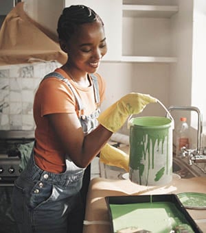 Painting, remodeling and black woman in home with bucket for diy project, renovation and creative decor. Interior design, happy and person with color for kitchen improvement, styling and maintenance