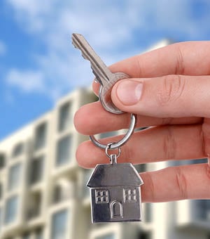 Real estate agent holding house key against building outdoors, closeup