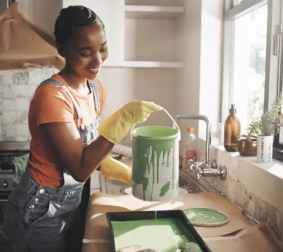 Painting, remodeling and black woman in home with bucket for diy project, renovation and creative decor. Interior design, happy and person with color for kitchen improvement, styling and maintenance