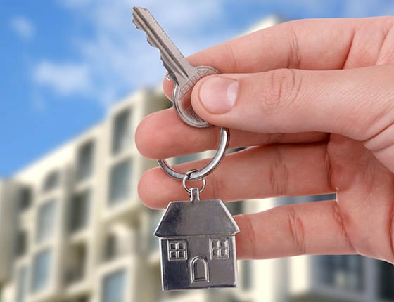 Real estate agent holding house key against building outdoors, closeup